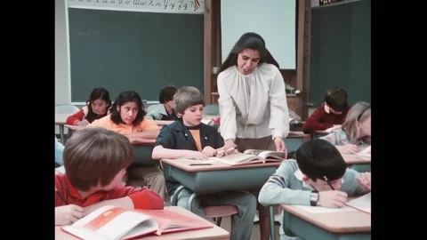 USA - 1982 - In this documentary, a teacher helps a boy find a page in a book. Stock Footage 328180340