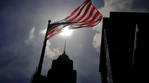 USA American flag waving backlight buildings sun light sky dark blue slow motion Stock Footage