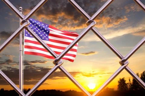 USA flag and migration border fence against the sunset Illustrazione stock