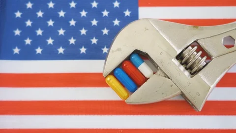 The USA flag with the silver wrench and the medicine capsules Stock Footage 129339280