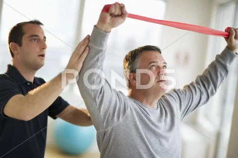 USA, New Jersey, Jersey City, Fitness instructor assisting man in gym Stock Photos