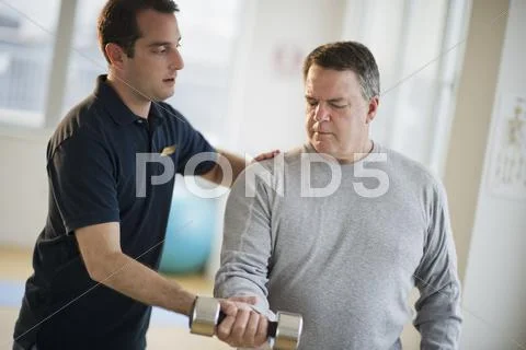 USA, New Jersey, Jersey City, Fitness instructor assisting man using hand weight Stock Photos