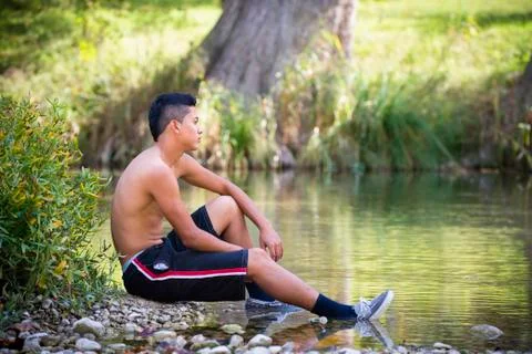 USA, Texas, Teenage boy sitting at Frio River Stock Photos