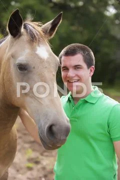 USA, Texas, Teenage boy stroking horse, smiling, portrait Stock Photos