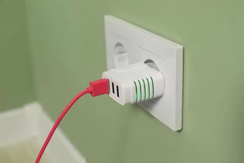 USB adapter with cable plugged into electric socket on light green wall, cl.. Stock Photos