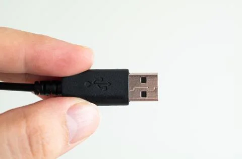 USB cable connector plug close up shot held between fingers by Caucasian male Stock Photos