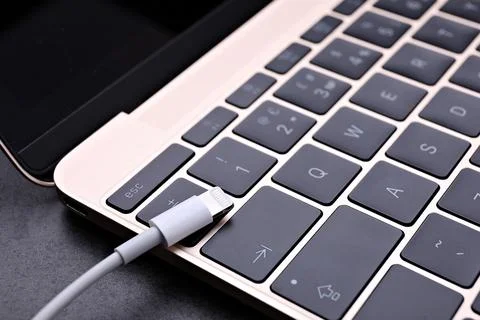 USB cable with lightning connector and laptop on black table, closeup Fotos Stock
