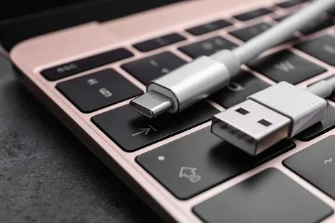 USB cable with type C connector and laptop on dark table, closeup Stock Photos