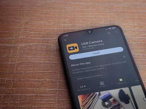 USB Camera app play store page on smartphone on wooden background Stock Photos