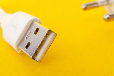 USB charger cable on yellow surface closeup often used for charging a smartph Stock Photos