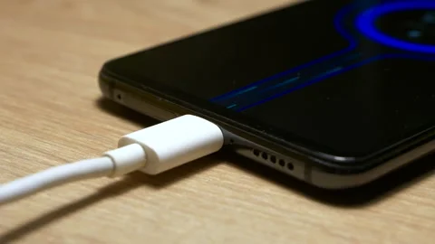 USB charging cable connected and transferring power to the modern smartphone. Vidéo 257253597