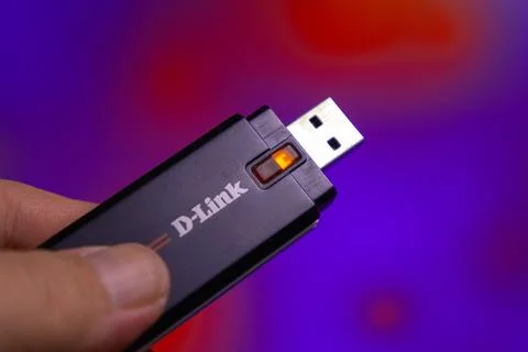 USB device from D-Link with a lit indicator in a hand against a colorful Stock Photos