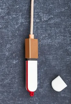 USB flash card is connected with USB cable, gray background. Close-up. Virtua Stock Photos