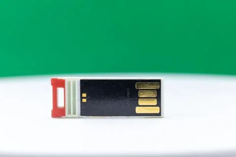A USB flash drive with a red connector is shown against a green background. Stock Photos