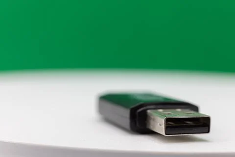 A USB flash drive is shown against a green and white background. Stock Photos
