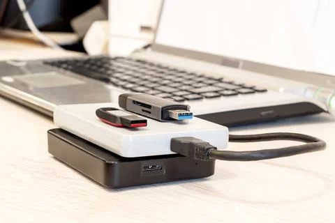 USB flash drives, external hard drives connected to a laptop on a desk for da Stock Photos