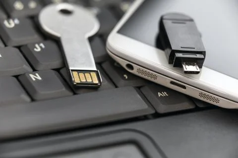 USB key and smartphone with micro USB flash drive on laptop keyb Fotos Stock