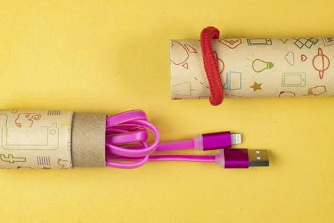 Usb lightning pink data cable in a cardboard tube close-up on yellow isolated Stock Photos