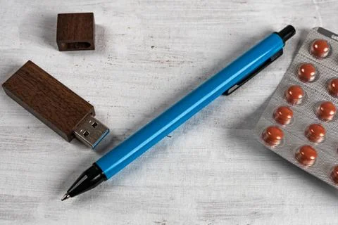 USB memory in a wooden case next to a pen and tablet on a gray structured bac Stock Photos