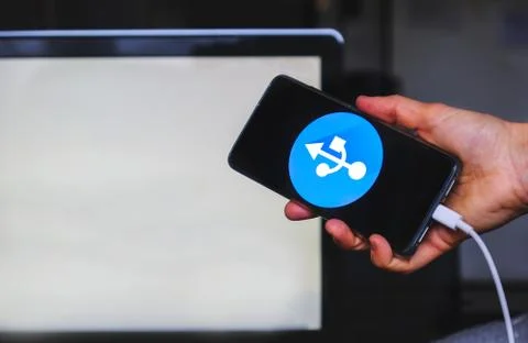 Usb tethering hand keep smartphone usb cable with white blank screen on Stock Photos