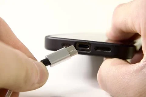 USB Type C cable and smartphone in hand Stock Photos