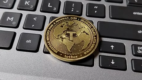 A USDT (Tether) token resting on a computer keyboard, illustrating stablecoin ad Stock Footage 340398469