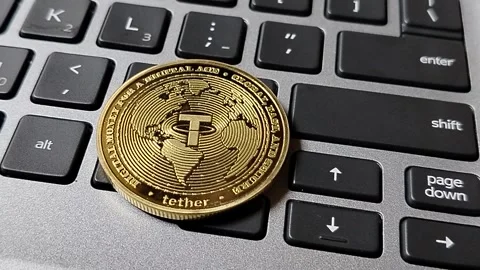 A USDT (Tether) token resting on a computer keyboard, illustrating stablecoin ad Stock Footage 340398470