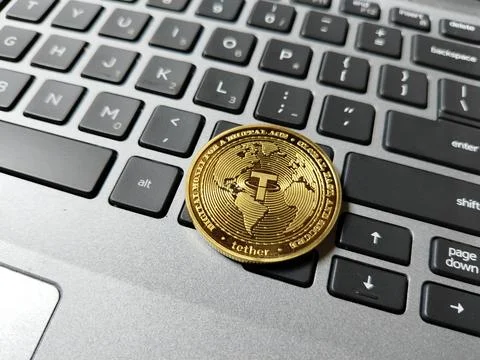 A USDT (Tether) token resting on a computer keyboard, illustrating stablecoin Foto stock