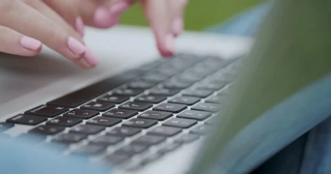 Use computer while sitting on the grass. Close-up of female hands typing on Stock Footage 195275249
