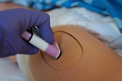 The use of an epinephrine auto-injector training device on a medical manneq.. Stock Photos