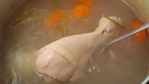 Use a fork to check if the chicken is cooked in the hot soup. Stock Footage 298350894