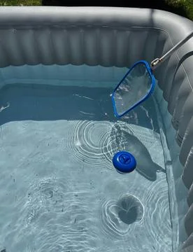 Use a hand net to catch dirt from the hot tub. Stock Photos