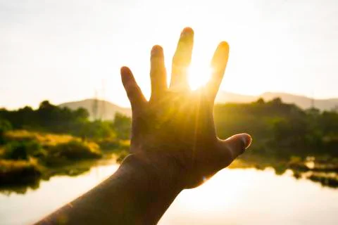 Use hand to touch the sun light in the morning, Pick up the sun by hand, Clos Stock Photos