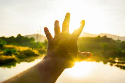 Use hand to touch the sun light in the morning, Pick up the sun by hand, Clos Stock Photos