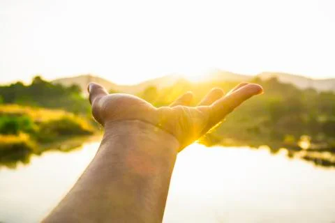 Use hand to touch the sun light in the morning, Pick up the sun by hand, Clos Stock Photos