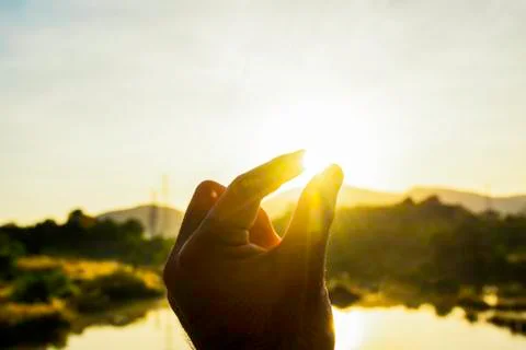Use hand to touch the sun light in the morning, Pick up the sun by hand, Clos Stock Photos