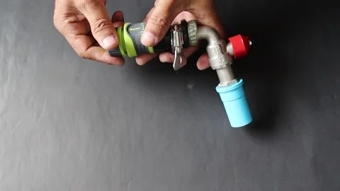 Use hands holding quick water faucet connector hose with metal faucet Stock Footage 147256602