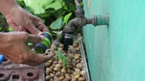 Use hands holding quick water faucet connector with blue rubber hose Stock Footage 148038284