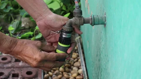 Use hands holding quick water faucet connector hose with metal faucet Stock Footage 148038292