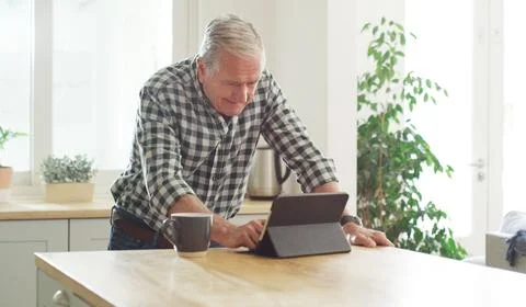 Use it for checking the news and so much more. a senior man using a digital Fotos de archivo