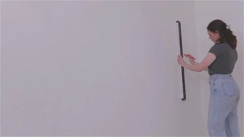 Use a level or plumb bob to draw a straight vertical line on the wall surface Video stock 335414505