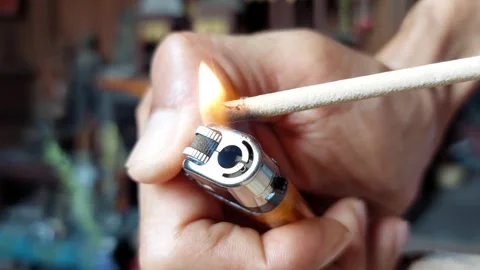 Use a lighter to light one incense stick Stockbeeldmateriaal 270022045