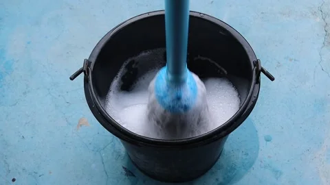 Use a mop in the black bucket to clean the cement floor Stock-Footage 163073704