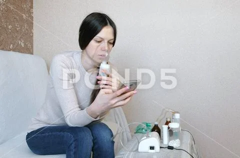 Use nebulizer and inhaler for the treatment. Young woman inhaling through Stock Photos