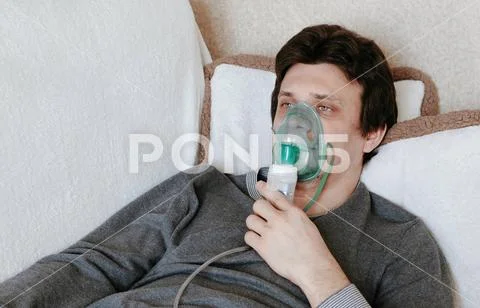 Use nebulizer and inhaler for the treatment. Young man inhaling through inhaler Stock Photos