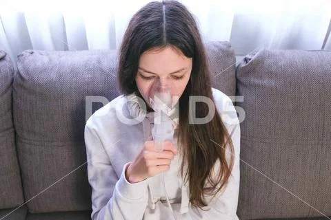 Use nebulizer and inhaler for the treatment. Young woman inhaling through Stock Photos