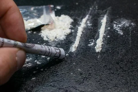 Use from a plastic bag of cocaine through a breathing tube from a hundred dollar Stock Photos