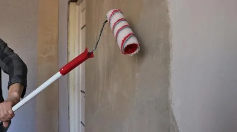 Use of a roller on an elongated handle in the process of repairing a room Stock Photos