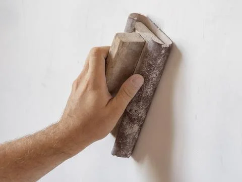 Use sandpaper to sand the wall surface. Surface leveling, work inside the hou Stock Photos