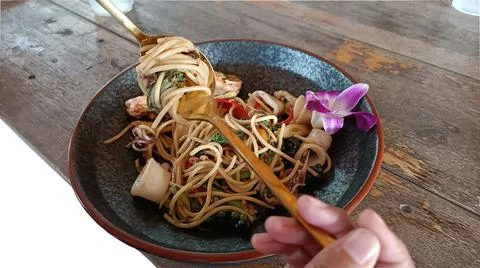 Use a spoon and fork to roll hot spicy spaghetti with seafood Foto stock